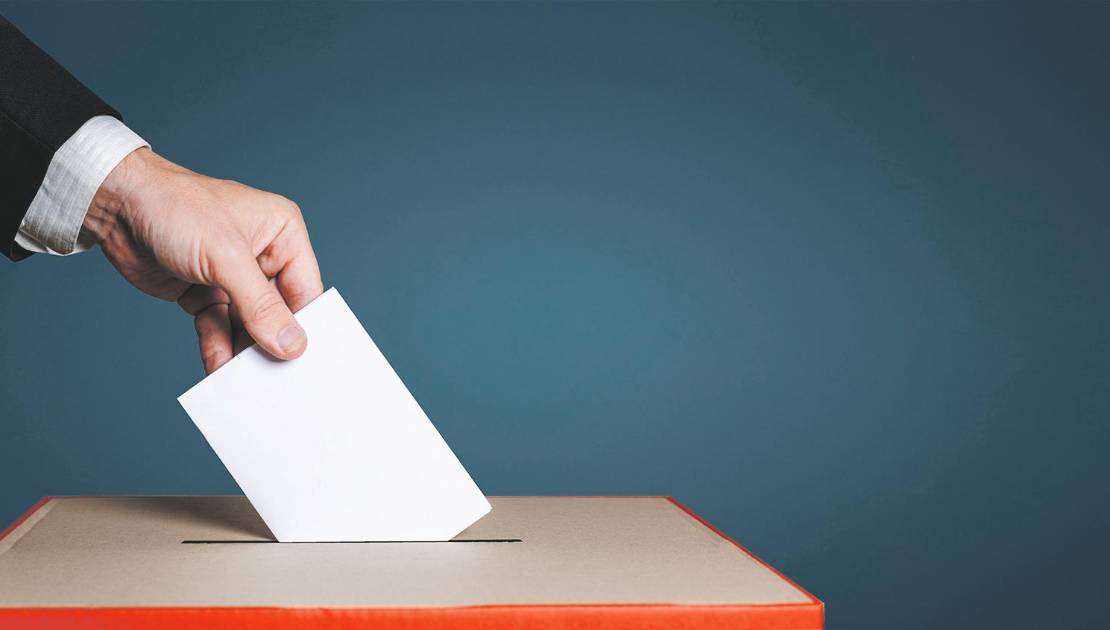 Moins d’élus par acclamation aux élections municipales 2025 Voter Holds Envelope In Hand Above Vote Ballot On Blue Background. Freedom Democracy Concept