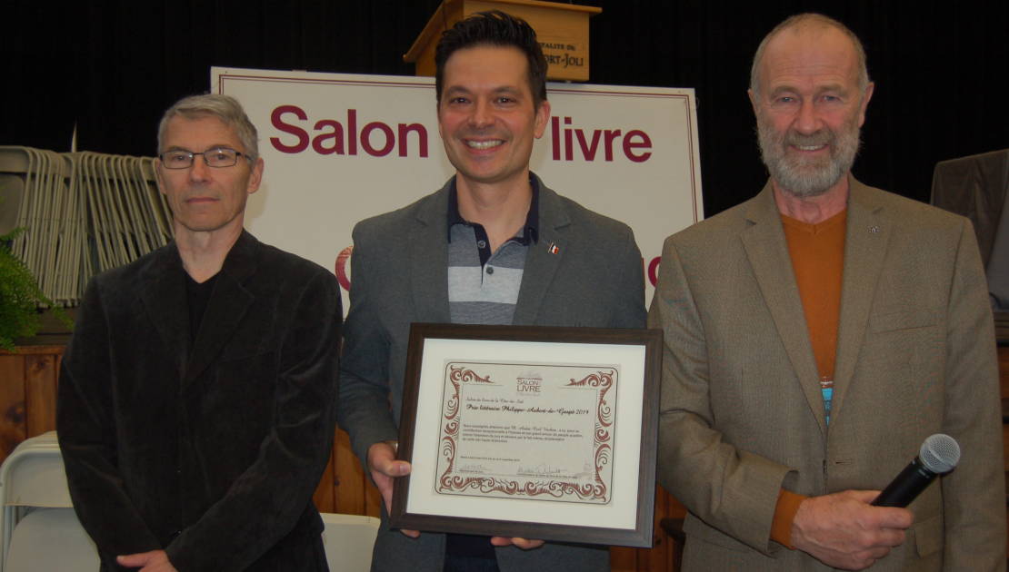 L’auteur André-Carl Vachon a reçu le 14e prix Philippe-Aubert-de-Gaspé et une bourse de 1 500$ des mains de M. Yves Hébert (à gauche), président d’honneur du Salon du livre de la Côte-du-Sud, et M. Jude Des Chênes, représentant du jury.
