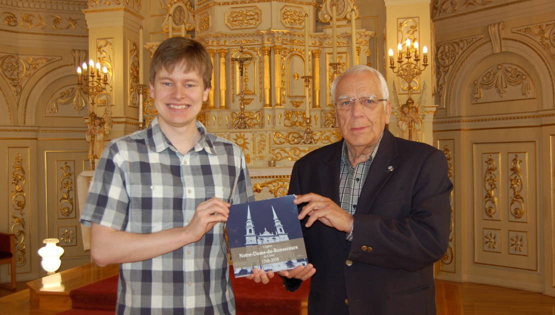 M. Tristan Morin (à gauche) présente le livre «L’église de Notre-Dame-de-Bonsecours de L’Islet 1768-2018» à M. Alyre Bois, président de la Fabrique Notre-Dame de Bonsecours.