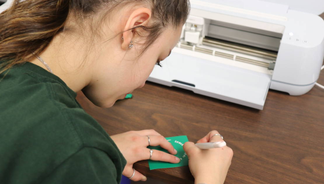Une élève produit des étiquette avec le logo de l'école à l'aide la machine CriCut.