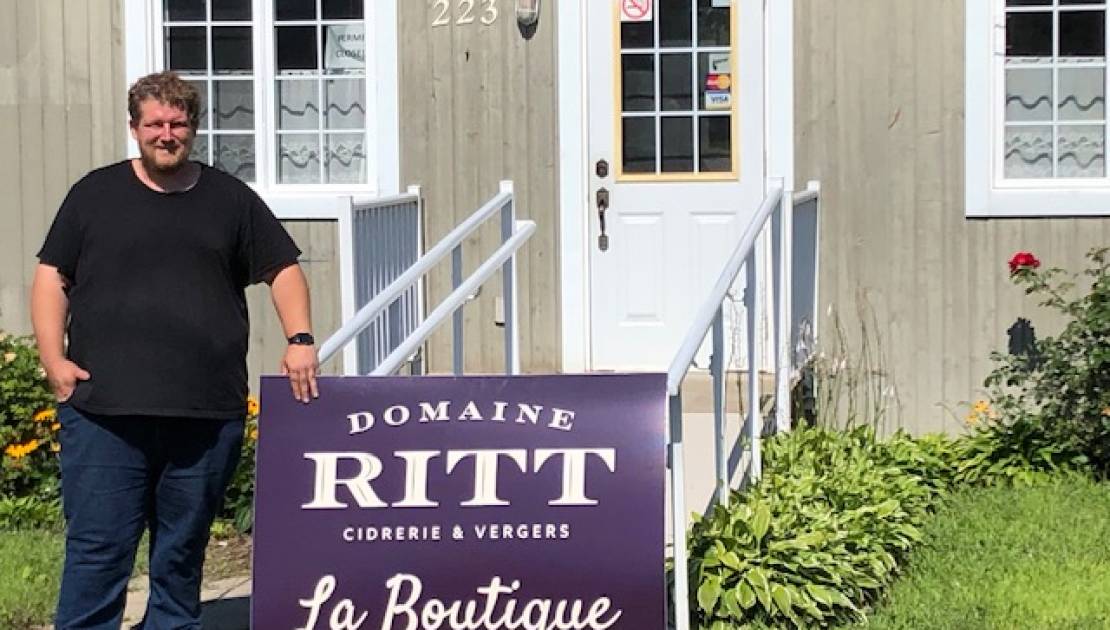 Sur la photo, on aperçoit Jean-François Ritt devant l’ancien bureau touristique de Cap-Saint-Ignace devenu une boutique pour les produits du Domaine Ritt.