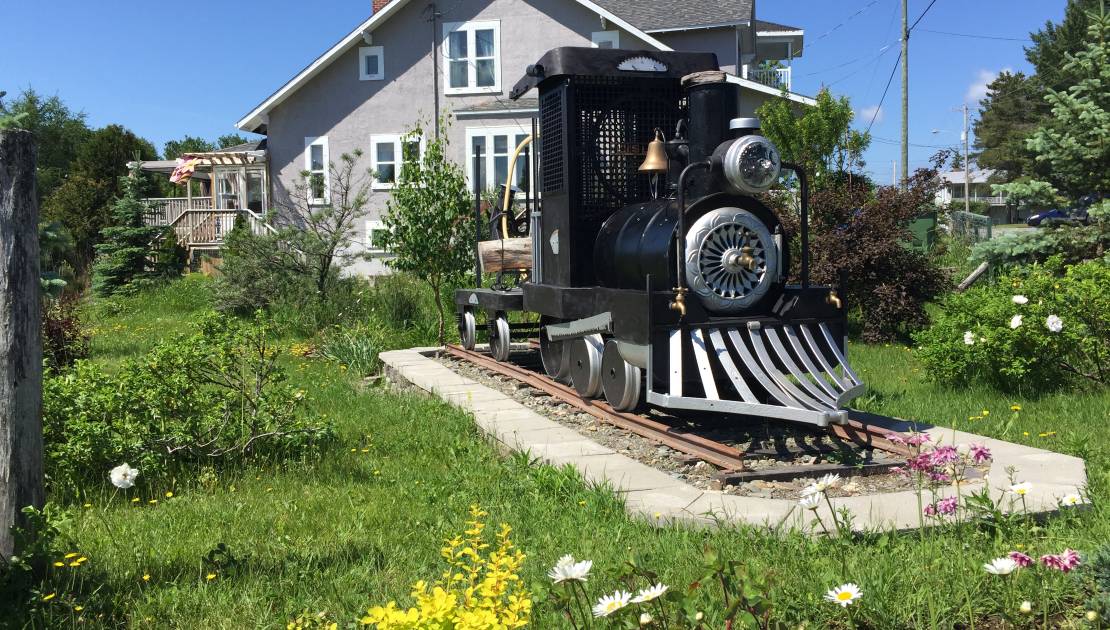 Cette sculpture, réalisée par Richard Thériault, est entièrement constitué de pièces recyclées. Il s'agit d'une oeuvre représentative du chemin de fer à l'époque florissante de l'industrie forestière à Lac-Frontière.