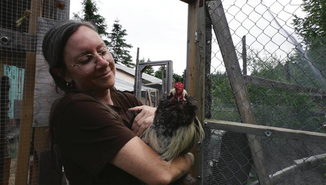 Geneviève Théroux accompagnée d’une de ses poules.