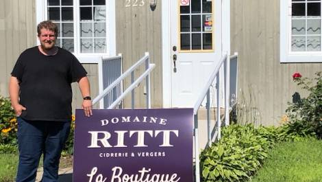 Sur la photo, on aperçoit Jean-François Ritt devant l’ancien bureau touristique de Cap-Saint-Ignace devenu une boutique pour les produits du Domaine Ritt.
